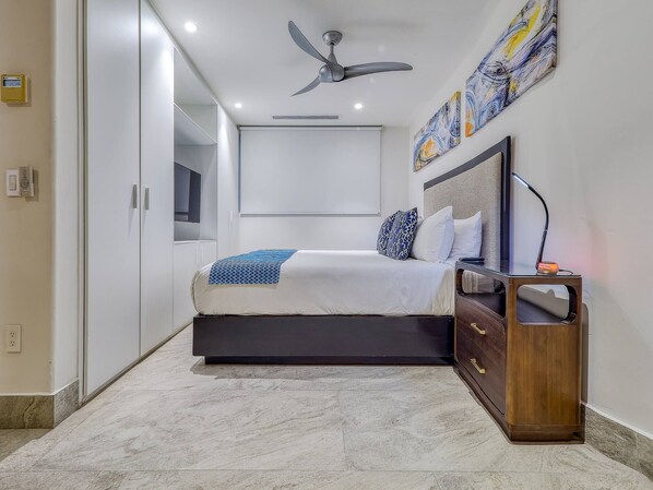 A modern bedroom with a bed, bedside table, and ceiling fan.