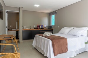Ein Hotelzimmer mit Bett, Schreibtisch, Stuhl, Mikrowelle und Fenster.
