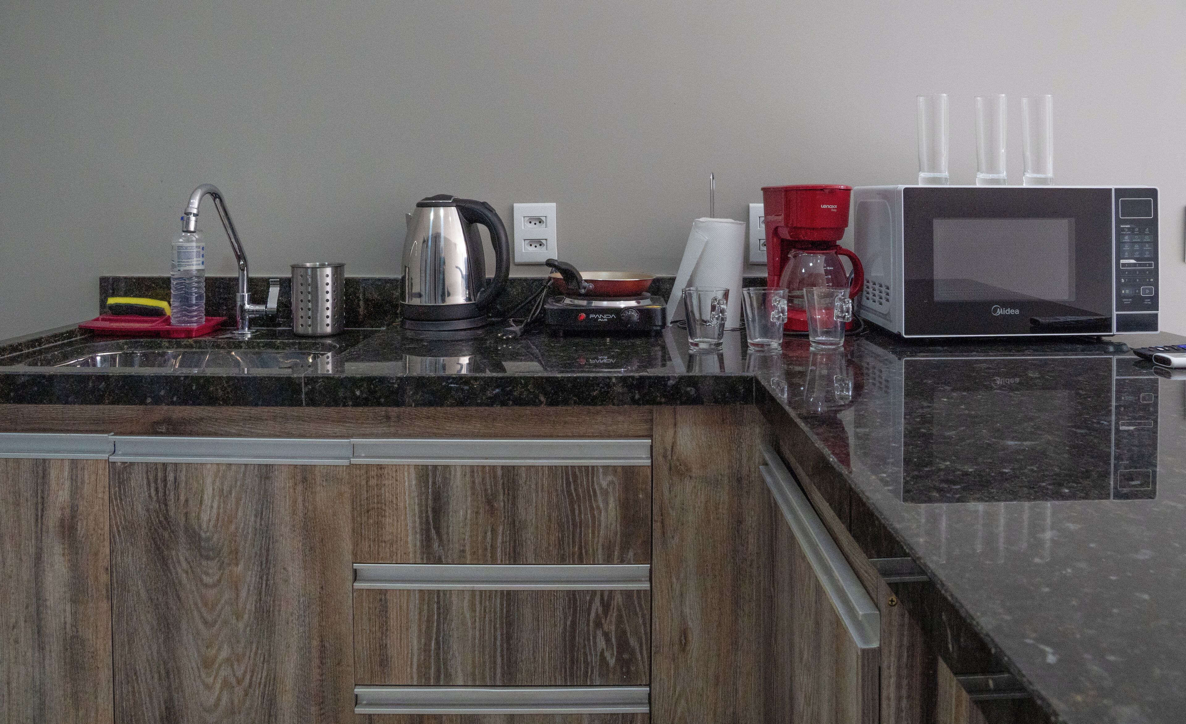 Une cuisine équipée d’un plan de travail en granit, d’une bouilloire, d’une machine à café et d’un four à micro-ondes.