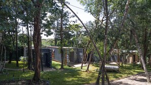 A rustic outdoor setting with a small cabin and a metal structure, surrounded by trees and grass. - Vila Ecco Cubo (Alto Paraiso de Goias)