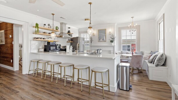 A modern kitchen with a white island, bar stools, and a ceiling fan.