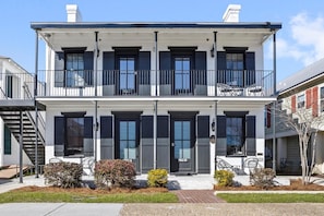 A two-story residential building with a balcony, a front door labeled '782 B', and a small front yard with shrubs.