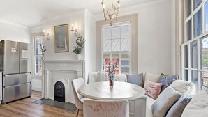 A modern kitchen with a round dining table, white walls, and a fireplace.