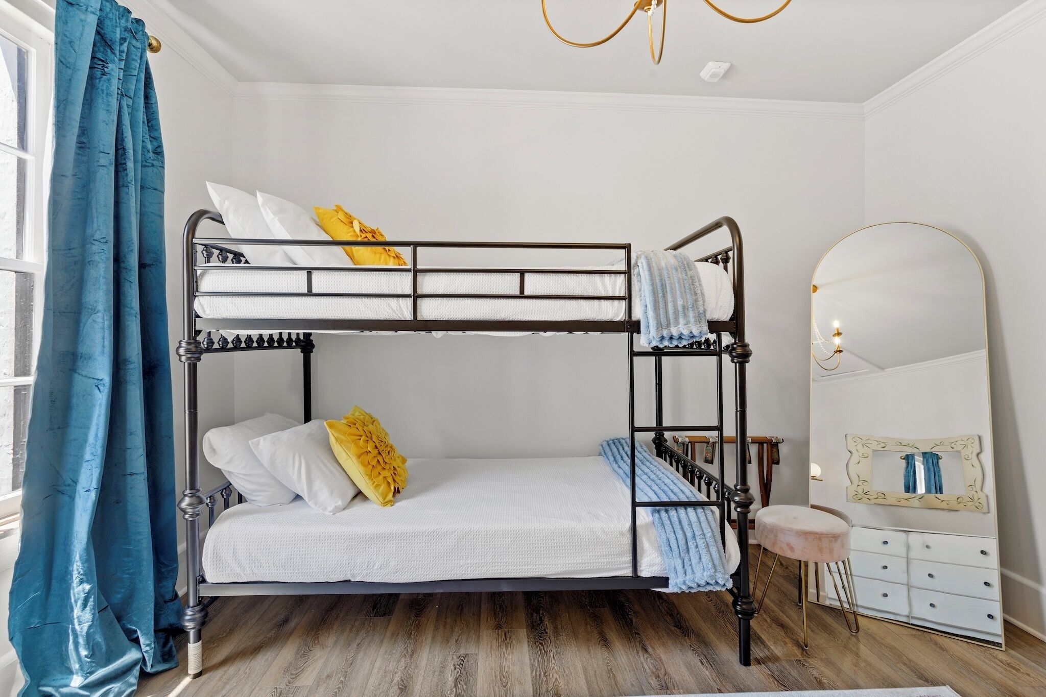 A bunk bed room with a mirror and dresser.