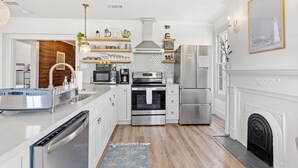 A modern kitchen with stainless steel appliances, white cabinetry, and a wooden accent wall.