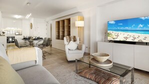Una sala de estar moderna con un televisor de pantalla plana, una mesa de centro de vidrio y un sofá.