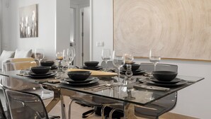 Un comedor moderno con una mesa de vidrio dispuesta para cuatro personas, rodeada de sillas.