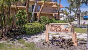 A Playa Encantada Resort tábla, melyről jól láthatók a környező pálmafák, a háttérben pedig egy többemeletes épület is megfigyelhető.