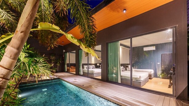 Una villa moderna con piscina, amplios ventanales correderas y plantas tropicales.