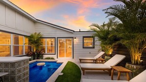 A modern house with a swimming pool, lounge chairs, and potted plants. - 83rd St Villas West 2 Bedroom Villa (Holmes Beach)