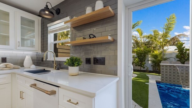 A modern kitchen with white cabinetry, a built-in sink, and wooden shelves above the counter. - 83rd St Villas West 2 Bedroom Villa (Holmes Beach)
