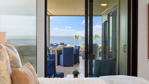 A bedroom with a large sliding glass door leading to a balcony with a view of the ocean. - Wailea Elua 2007 1 Bedroom Condo (Kihei)