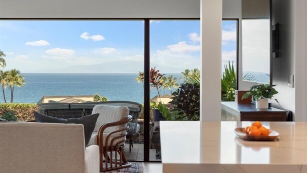 A modern living room with a large window offering a view of the ocean. - Wailea Elua 2007 1 Bedroom Condo (Kihei)