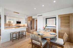 Una cocina moderna con armarios blancos, una isla central y un comedor con una mesa redonda y sillas.