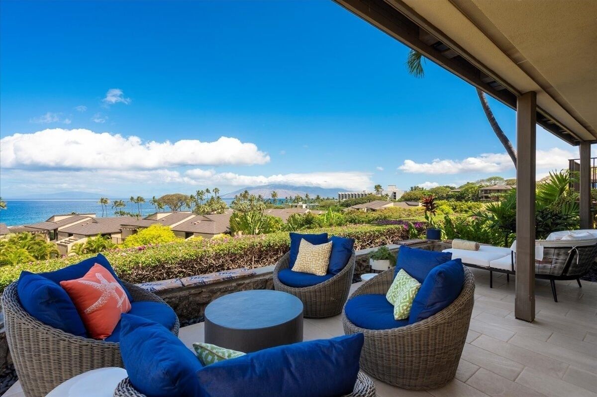 A patio with wicker furniture and a view of the ocean.