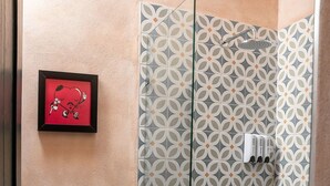 A bathroom with a toilet, a shower with a glass door, and a patterned wall.