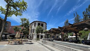 A courtyard with stone flooring, outdoor seating, and a fountain.