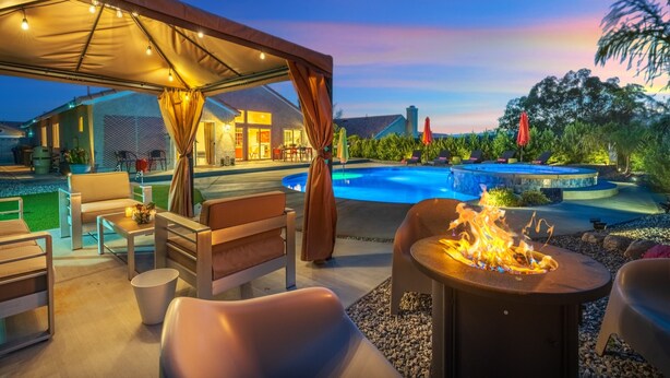 Uma área de estar ao ar livre com piscina, mobiliário e lareira.
