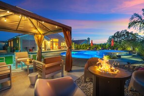 Un área de patio exterior con piscina, asientos y una chimenea.