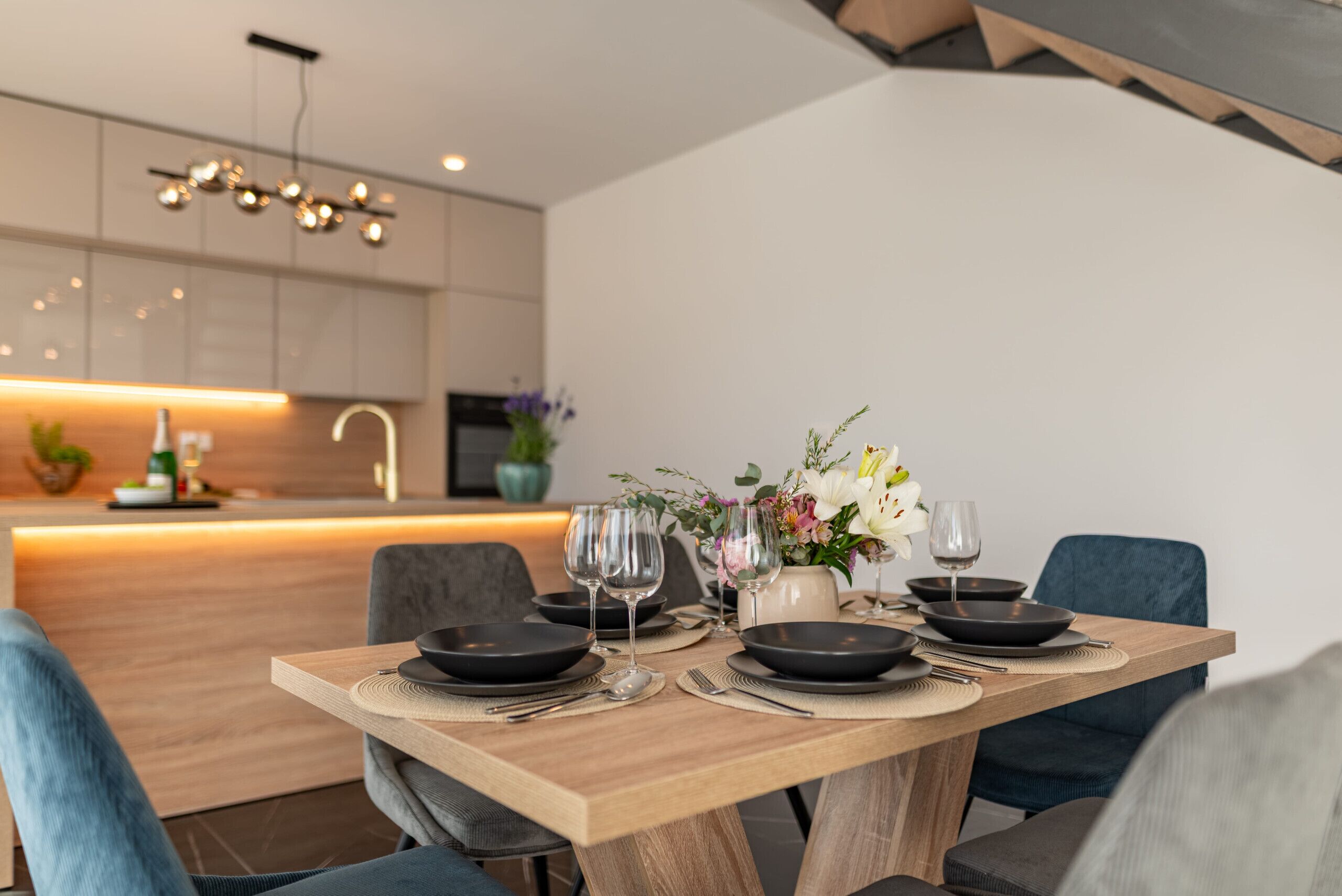 A dining table set with black plates, wine glasses, and a vase of flowers.