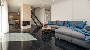 Un salon moderne avec un canapé gris, une table basse en bois et un sol carrelé de couleur noire.
