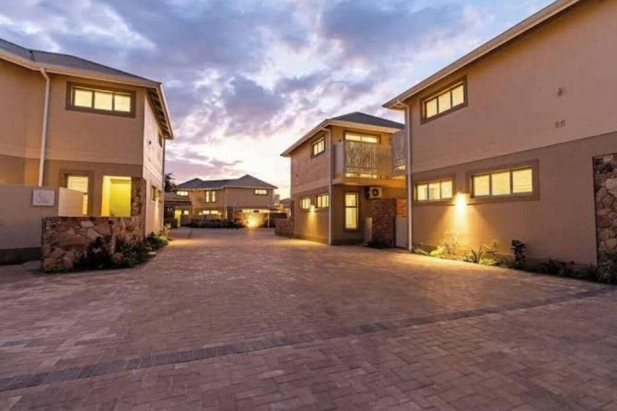 Un quartiere residenziale con diverse case a due piani, vialetti lastricati e illuminazione esterna.