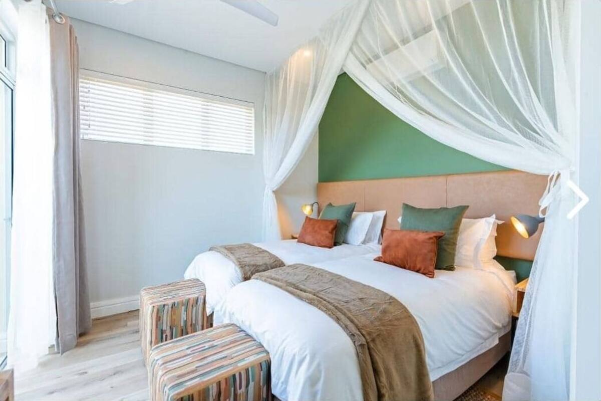 Una camera da letto con un letto, comodini, una finestra con persiane e una ventola a soffitto.