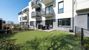 A modern apartment building with balconies, a patio area, and a well-maintained lawn. - Apartamenty Sun & Snow Nad Zalewem (Dziwnówek)