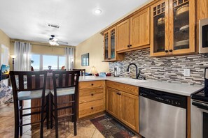 Una cocina moderna con armarios de madera, lavavajillas y salpicadero de azulejos.