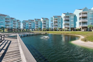 Un edificio residenziale sul lungomare, con numerosi balconi, un molo e una vista aperta sull'acqua.