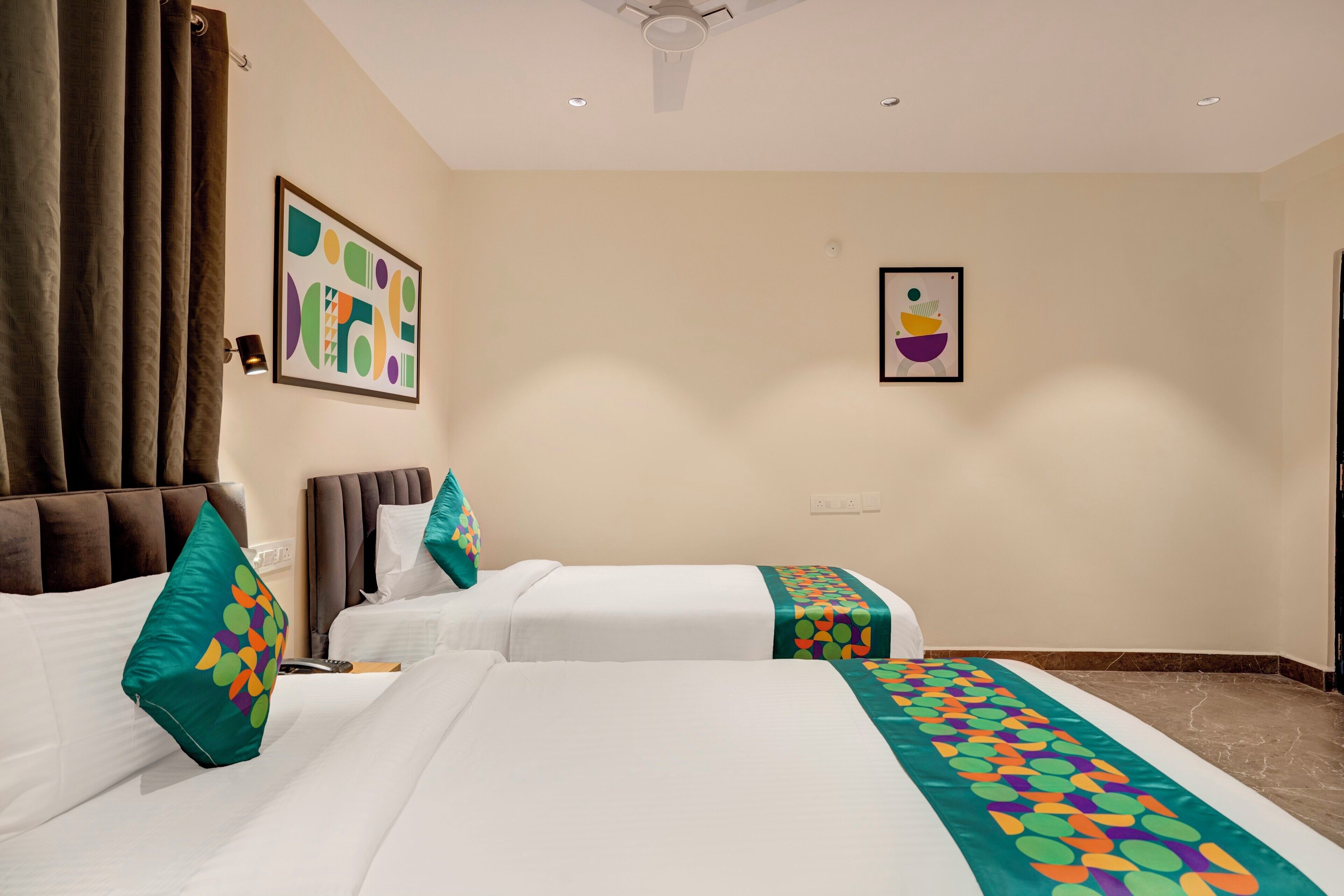 A hotel room with two beds, a ceiling fan, and artwork on the walls.