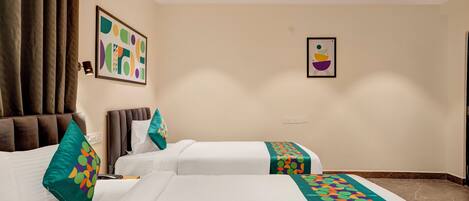 A hotel room with two beds, a ceiling fan, and artwork on the walls.