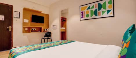 Une chambre d’hôtel équipée d’un lit, d’un bureau et d’un téléviseur fixé au mur.