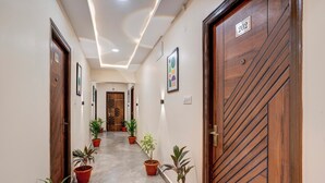 A hallway with potted plants, wooden doors, and a number sign. - Treebo Address Inn Gachibowli (Hyderabad)