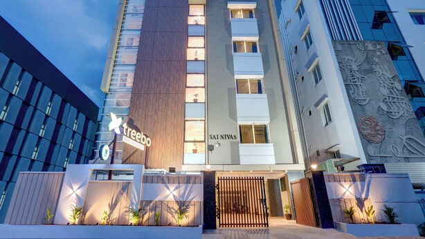 A modern hotel with a prominent 'tree' sign, a vertical wooden panel, and a 'SAI NIVAS' sign on the facade. - Treebo Address Inn Gachibowli (Hyderabad)
