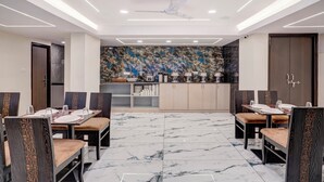 A dining area with a marble floor, modern chairs, and a decorative wall. - Treebo Address Inn Gachibowli (Hyderabad)