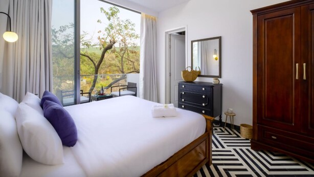 Habitación de hotel con una cama grande, un armario de madera, un escritorio y vistas al exterior.