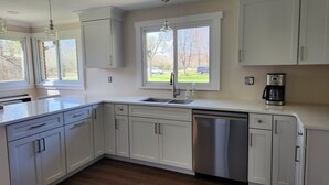 A modern kitchen with white cabinetry, a stainless steel dishwasher, and a coffee maker. - Charming 3-bedroom ranch with a covered back patio, in peaceful Grand Island (Grand Island)