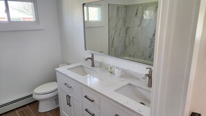 A modern bathroom with two sinks, a toilet, and a large mirror. - Charming 3-bedroom ranch with a covered back patio, in peaceful Grand Island (Grand Island)