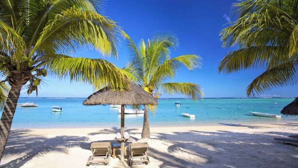 A beach with palm trees, a thatched umbrella, and lounge chairs. - Tropical 3-bedroom villa 5 min from the beach, perfect for families (Flic en Flac)
