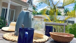 A patio with a table set for outdoor dining, featuring a coffee maker, a jar, and a basket. - Tropical 3-bedroom villa 5 min from the beach, perfect for families (Flic en Flac)