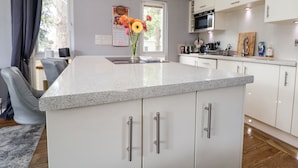 A modern kitchen with white cabinets, a granite countertop, and stainless steel appliances. - 155 Woodland Hall (Ruthin)