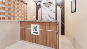 Uma receção com o logótipo 'treebo', uma parede de mármore e um aparelho de ar condicionado.