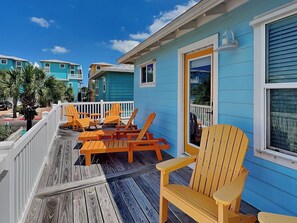 A wooden deck with outdoor seating and a view of a blue building.