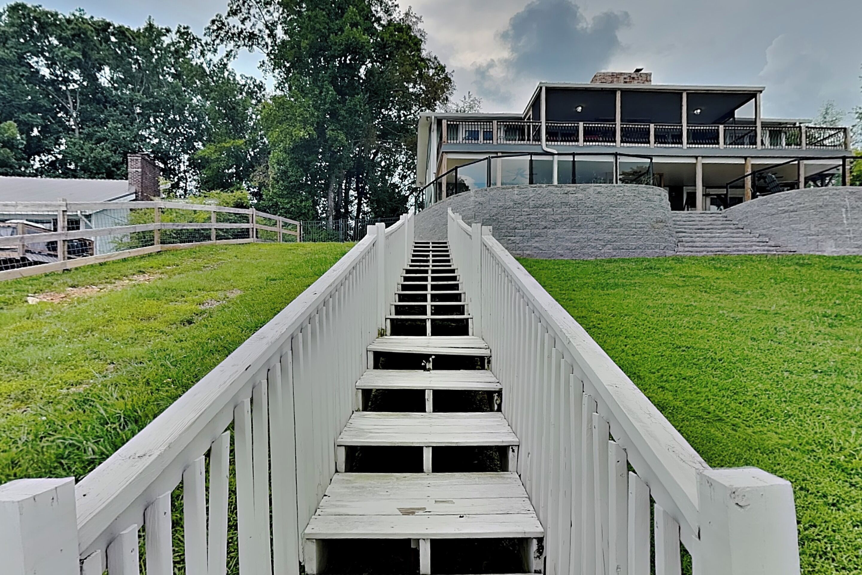 A wooden staircase leading to a building with a flat roof and a stone wall.