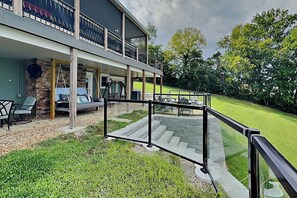A two-story building with a balcony, outdoor seating, and a grassy yard. - Sunset Cove | Pet-Friendly w/ Heated Pool + Game Room (Dandridge)