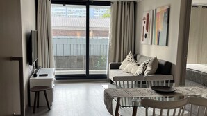A modern living room with a sofa, coffee table, and chairs. There is a sliding glass door leading to a balcony.