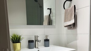 A modern bathroom with a white sink, a mirror, a towel rack, and a wooden cabinet.