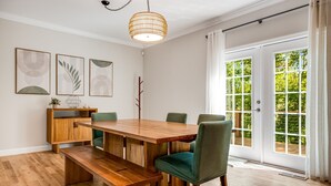 A dining area with a wooden table, green upholstered chairs, and a hanging light fixture.