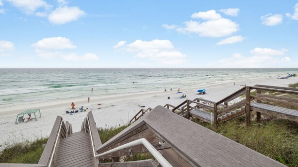A beach with wooden boardwalks leading to the shore, clear skies, and calm waters.